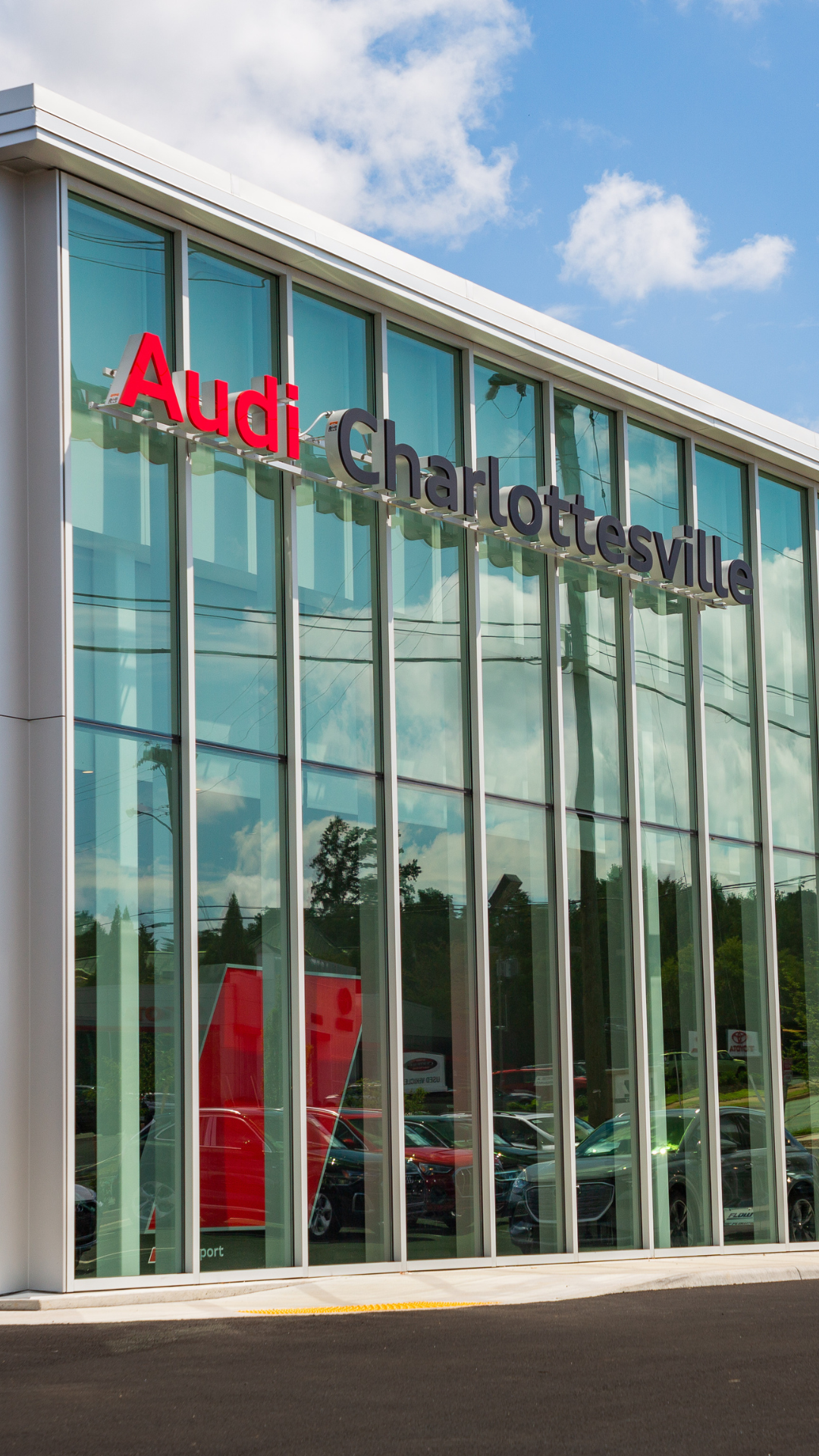 Audi Charlottesville dealership storefront with clouds in the background