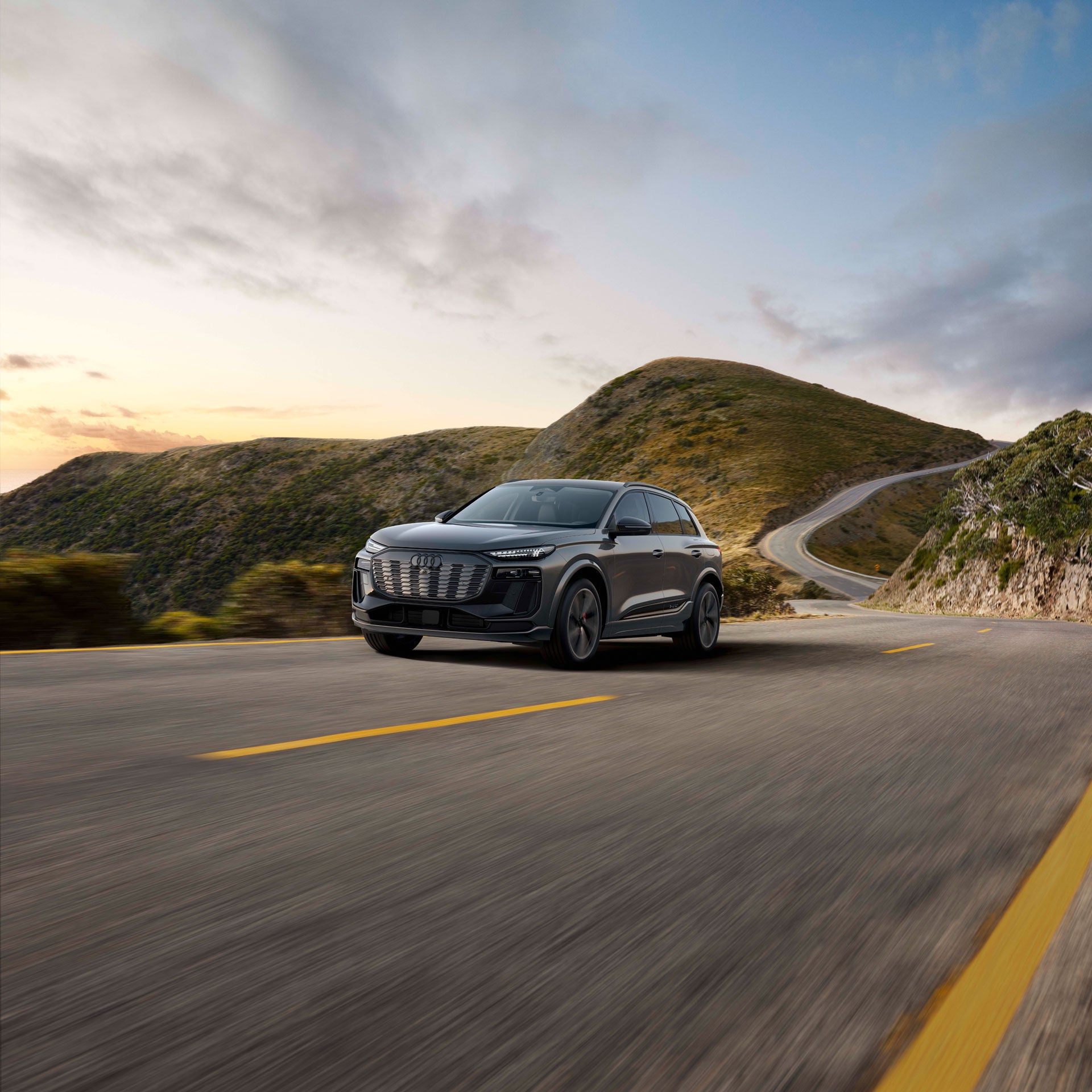 Vue avant d’un Audi Q6 Sportback e-tron noir stationné à l’extérieur d’un bâtiment moderne.