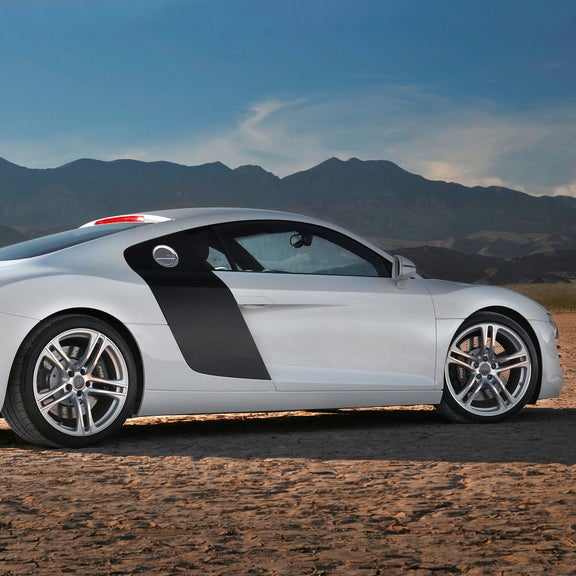 Side profile of a silver 1st-generation Audi R8 parked in the desert.