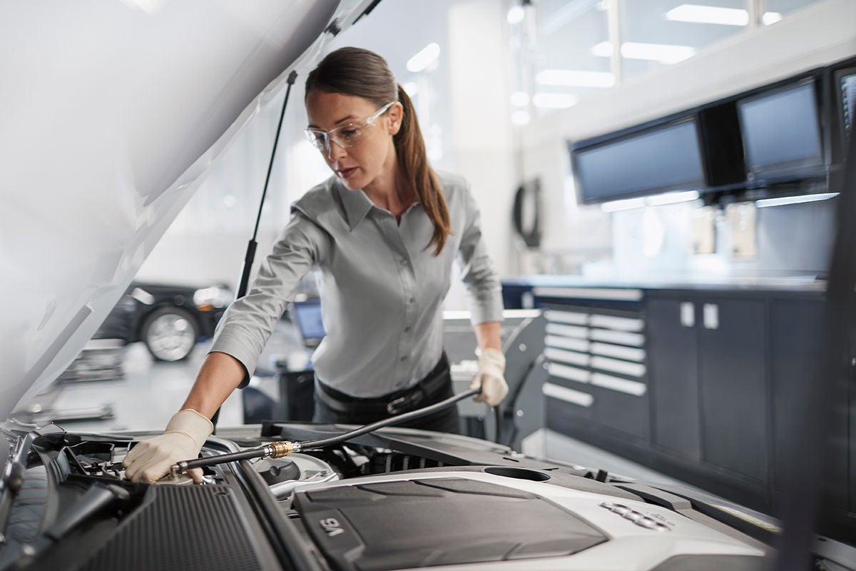 A technician checking the engine bay of an Audi during an oil service