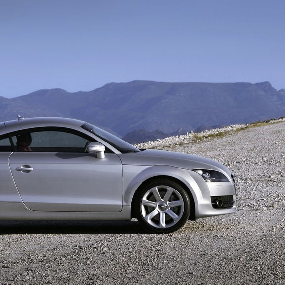 A silver Audi TT Coupe parked looking over a mountainous field.
