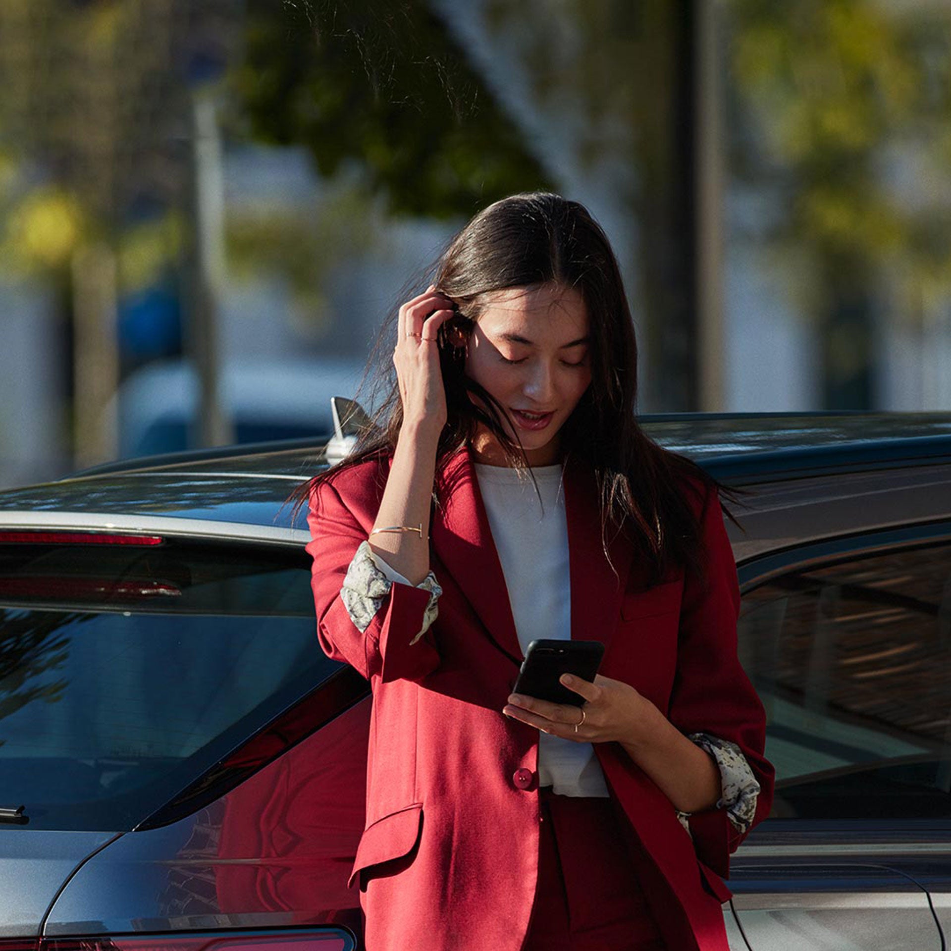 A woman standing in front of an Audi vehicle, looking down at her phone.
