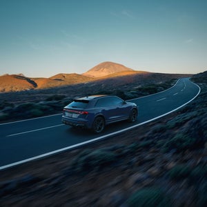 Aerial rear view of the Audi RS Q8 accelerating on a hillside road.