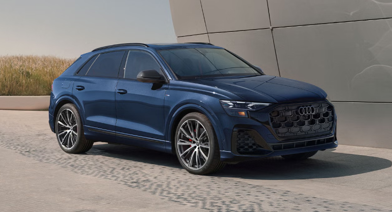 2026 Audi Q8 driving on paved road near modern building