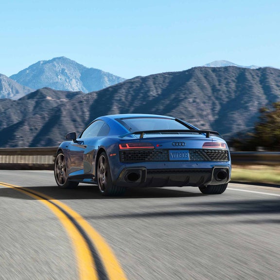 Rear view of the Audi R8 Coupe driving along a winding mountain road.