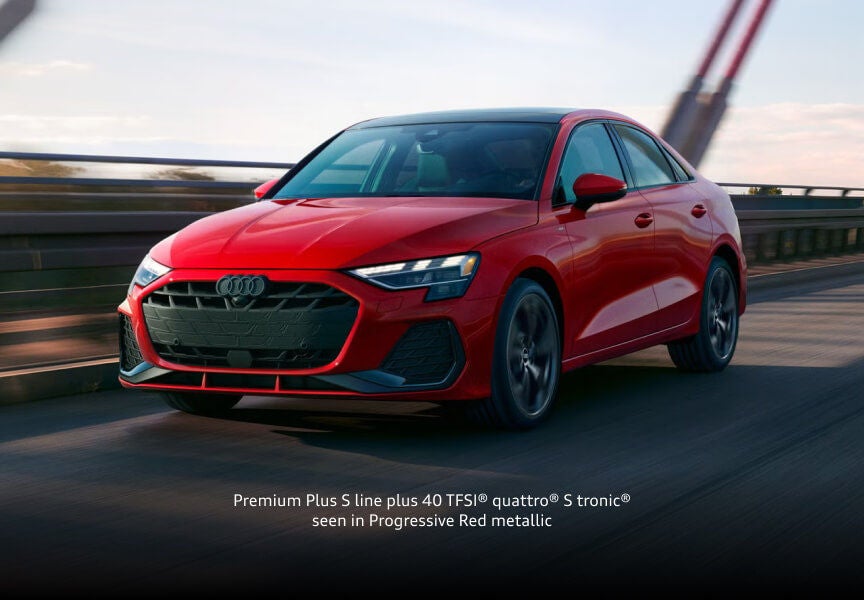 2026 Audi A3 Premium Plus S line in Progressive Red metallic, front three-quarter view driving across a bridge.