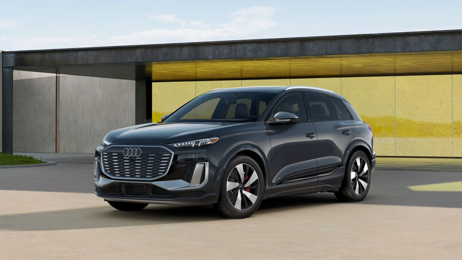 Black sq6 e-tron front-facing, towards the left with a yellow wall in the background.