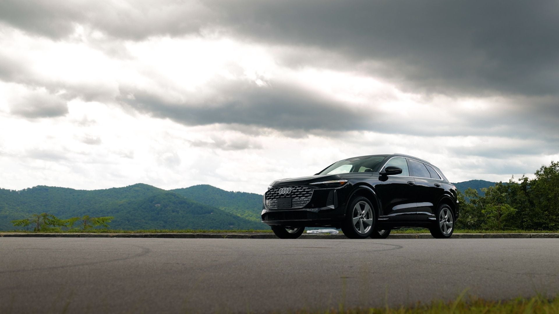 Front view of a new Audi Q5 SUV parked with a mountain range in the background. 