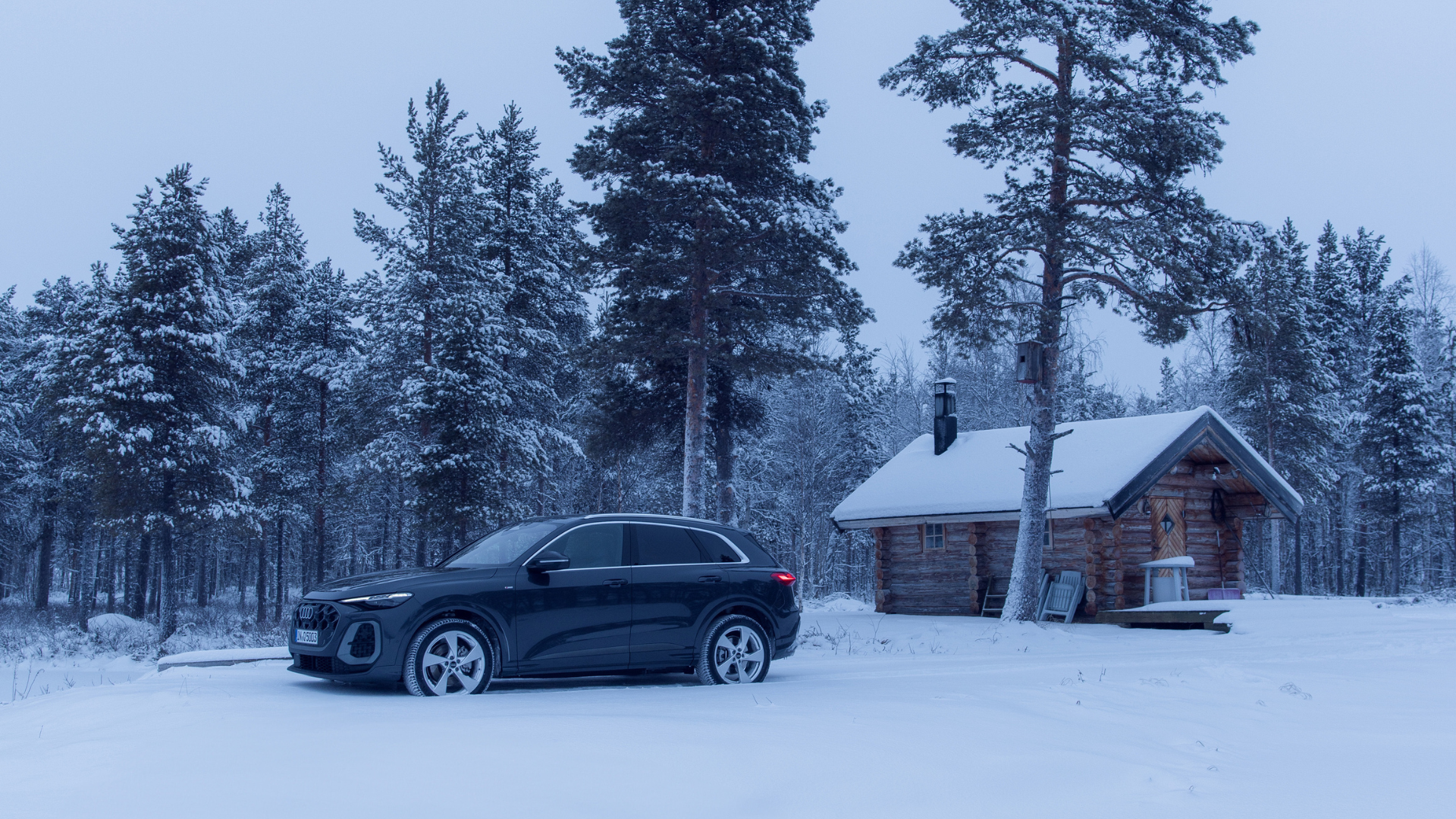 Audi by a log cabin in winter