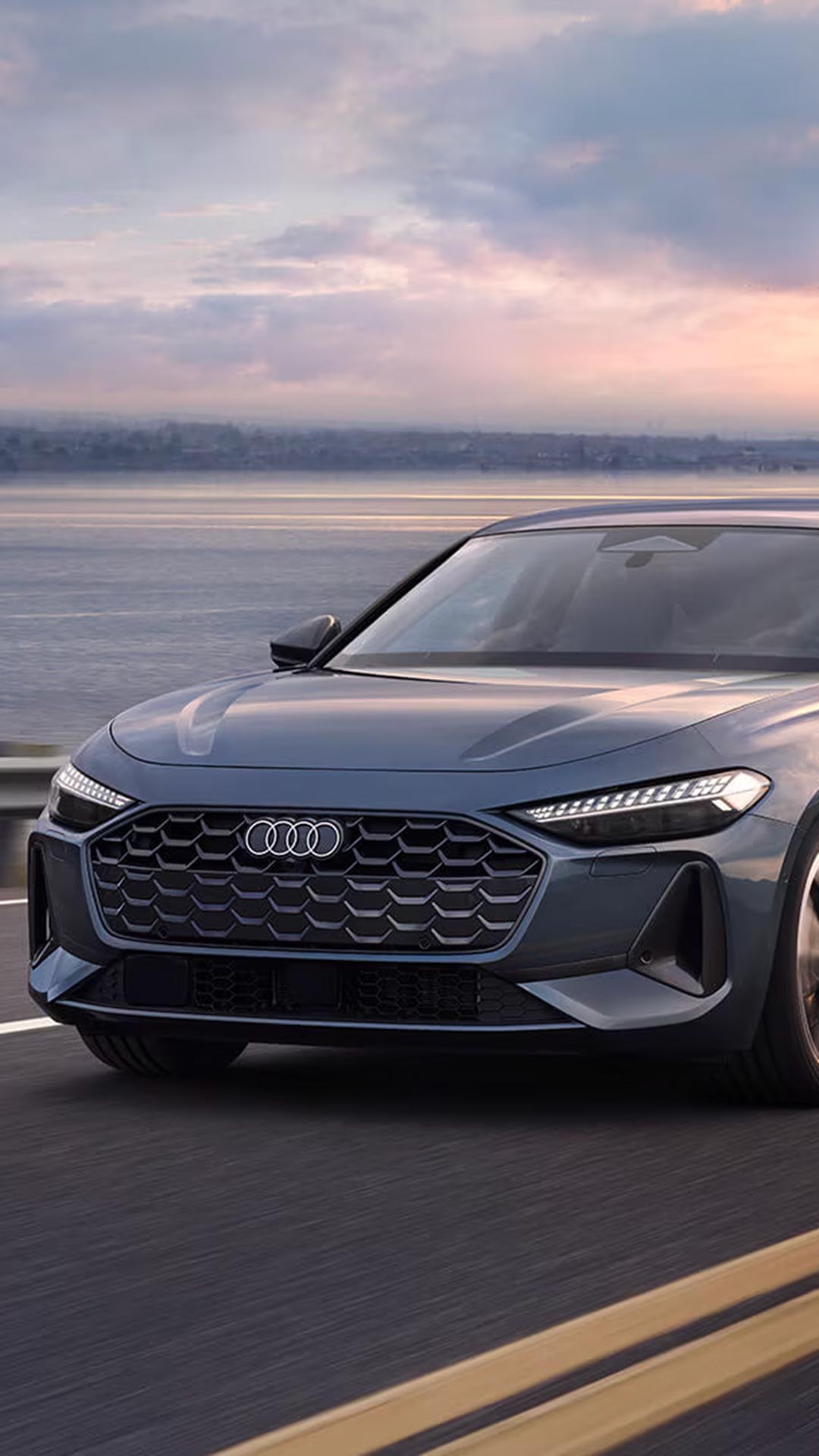 Three-quarter front view of an Audi driving on the road.