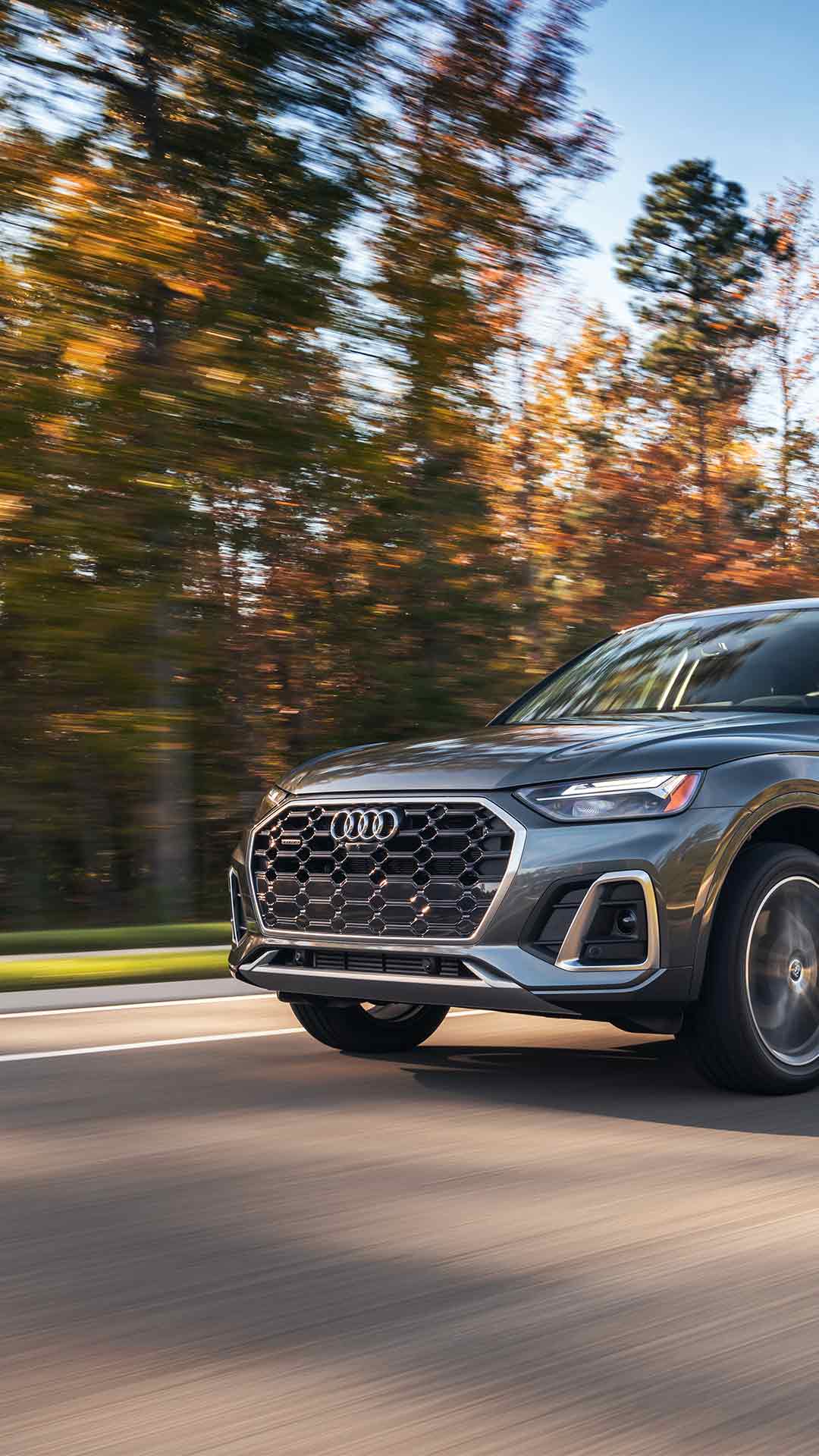 Three-quarter view of an Audi Q3 accelerating near a group of trees