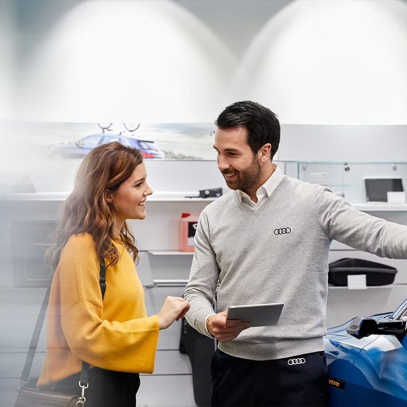 Service consultant speaking with a customer by a blue Audi