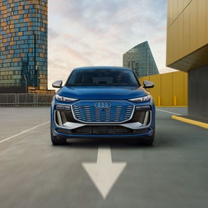 Front profile view of the Audi SQ6 Sportback e-tron accelerating, showing the daytime running lights on the headlights.