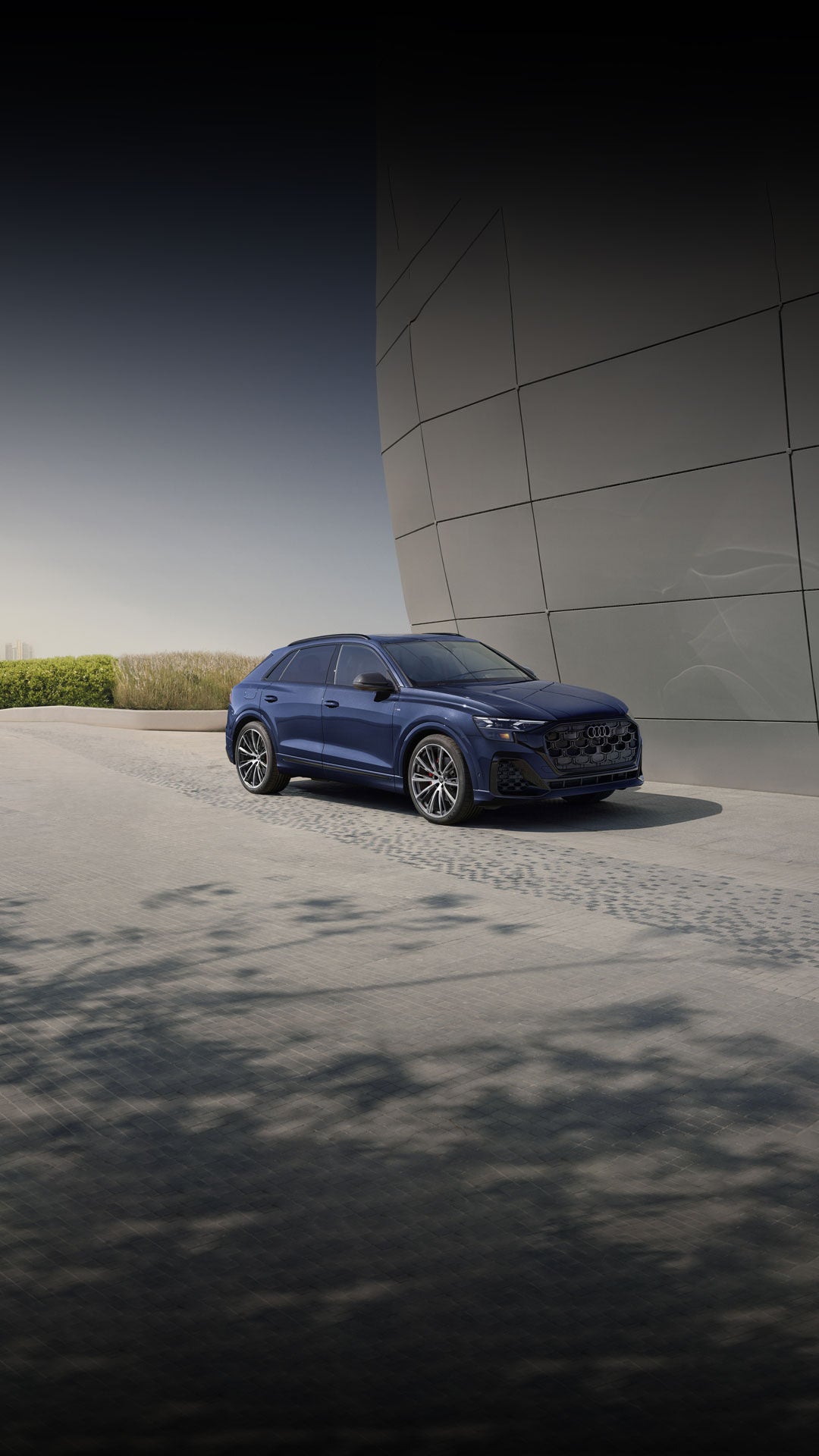 Three-quarter front view of the Audi Q8 parked by a modern building.