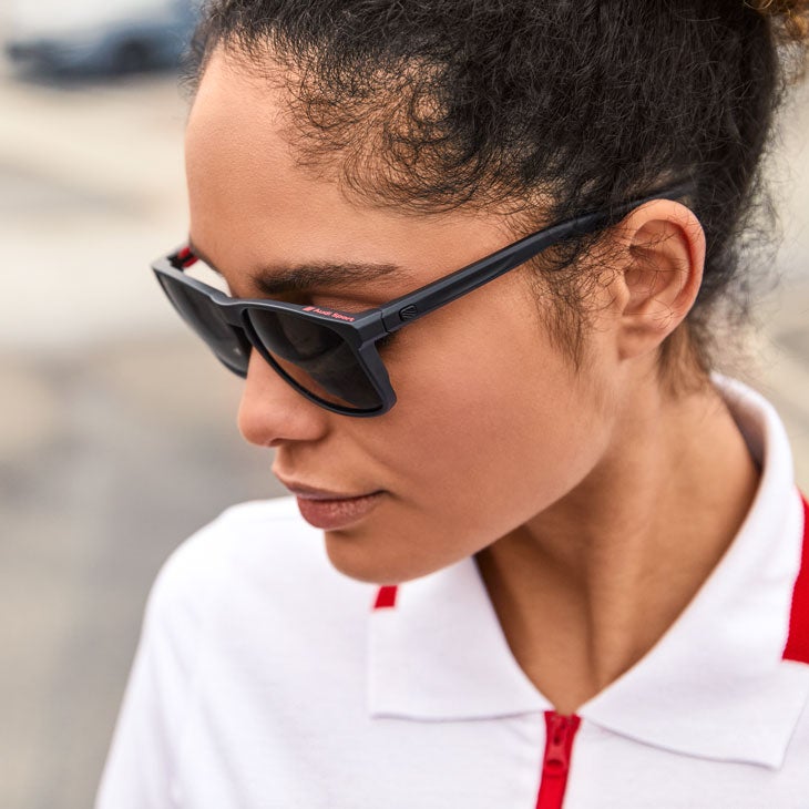 Side profile of a woman wearing Audi branded sunglasses and polo.
