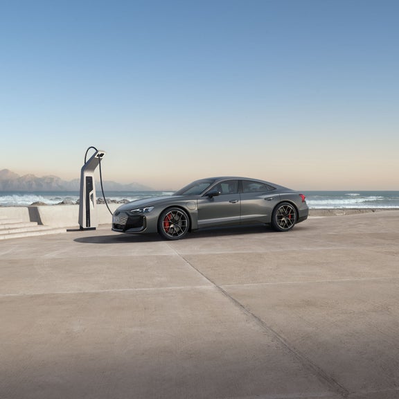 Three-quarter rear view of the Audi RS e-tron GT parked and charging. 