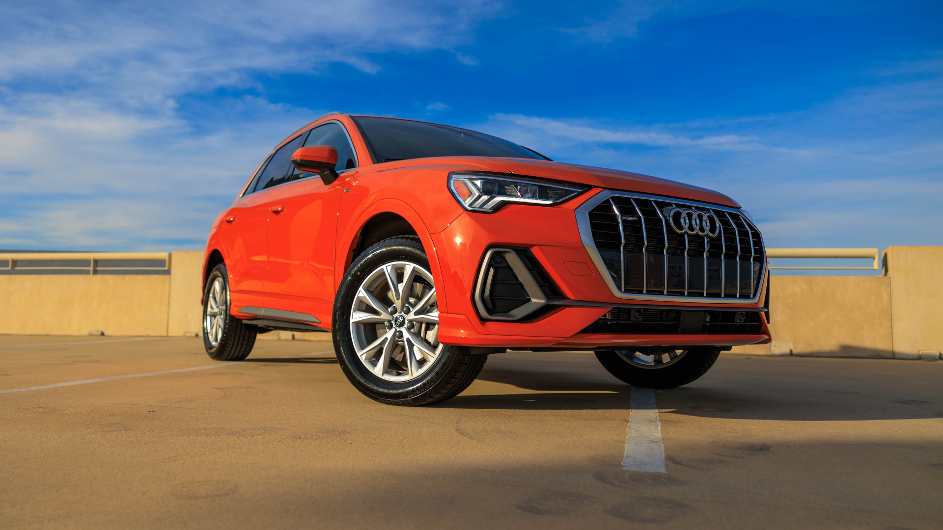 Orange Audi SUV parked with a blue sky in the back ground