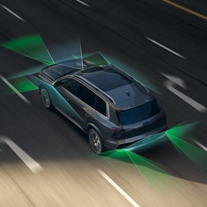 The Audi Q9 SUV, viewed from a diagonal angle above on a four-lane road. From the rear and the front, green and blue vectors divide the areas behind and in front of the vehicle.