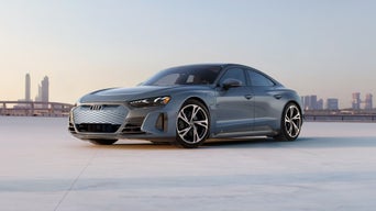 Photo of an Audi e-tron GT parked in front of a city skyline.