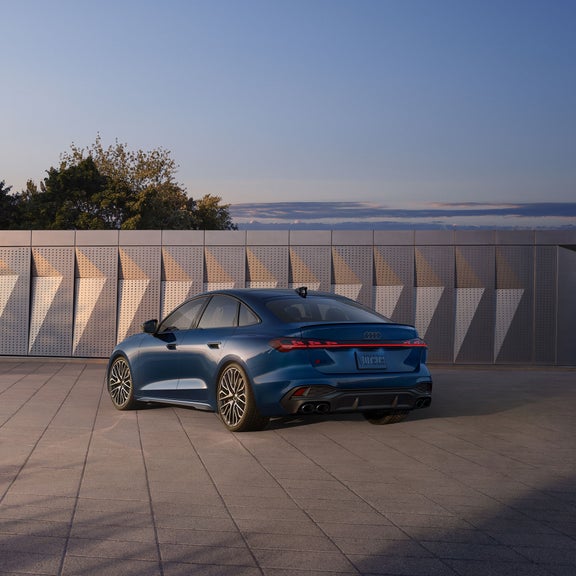 Three-quarter rear view of the Audi S5 parked in front of a modern building.