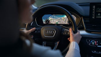 Close-up of a person clinging to the steering wheel of an Audi vehicle.
