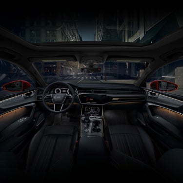 Interior view of an Audi vehicle with the interior lighting package plus, illuminated in a soft yellow glow.