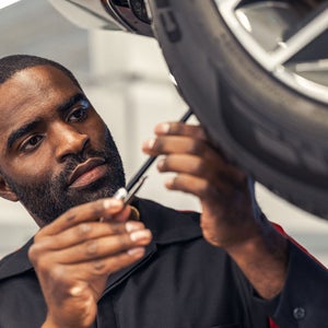Technician measuring tire depth