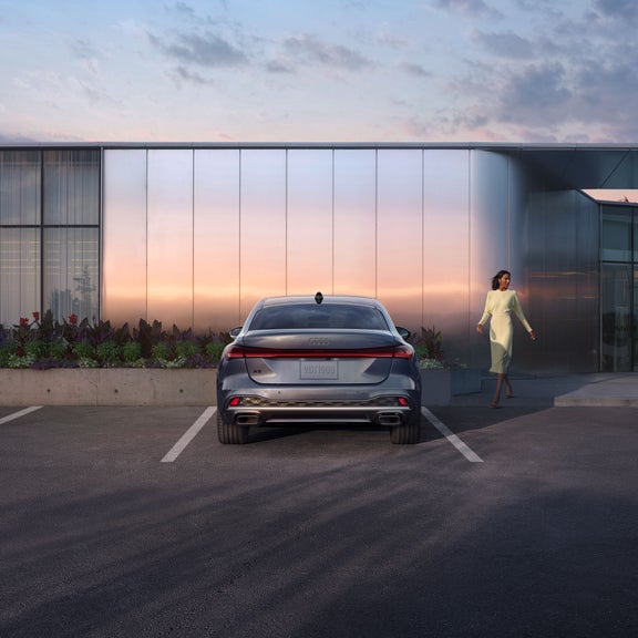 Plan arrière de profil de l’Audi A5 avec une personne qui marche vers le véhicule.