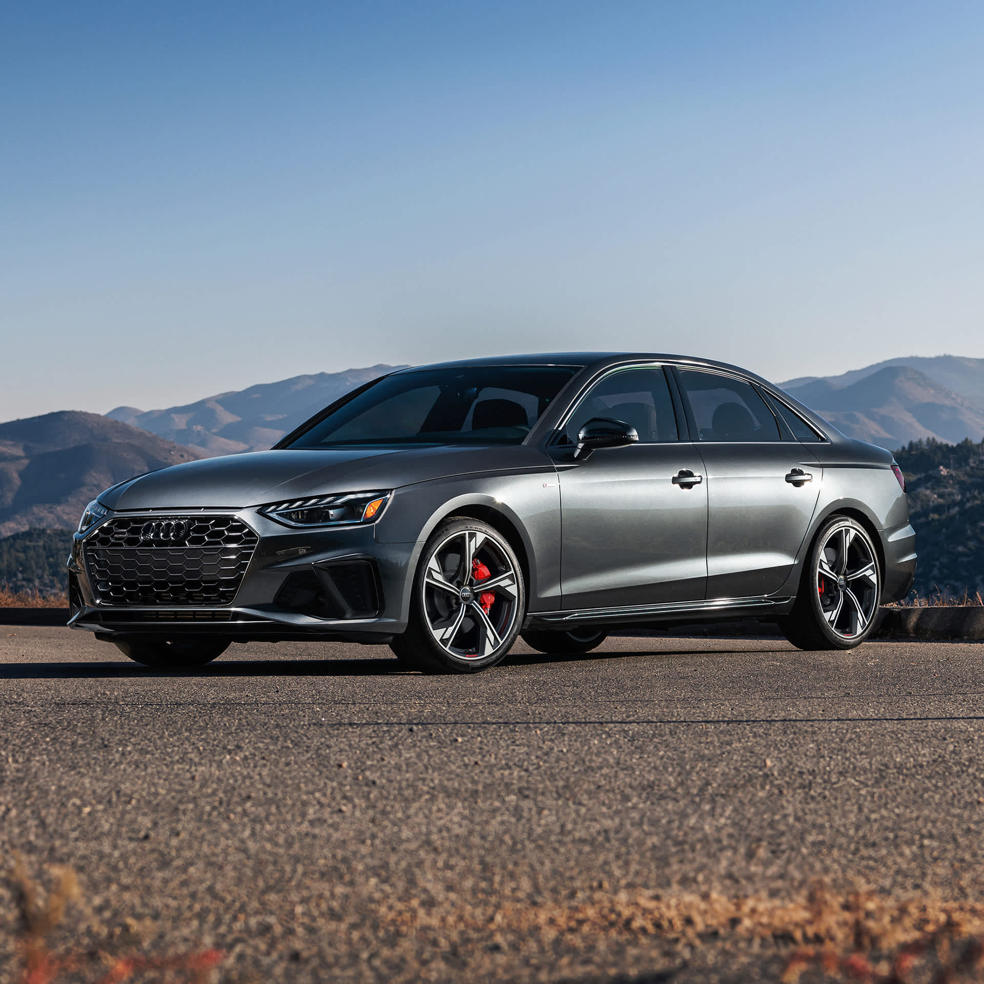 Exterior side profile view of an Audi A4 accelerating and a BMW Series 3, parked.