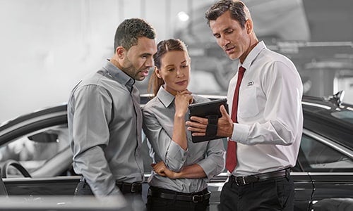 Audi sales representatives looking over leasing options for customer