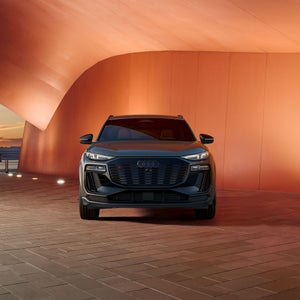 Front profile of the Audi SQ6 e-tron parked in front of a modern building.