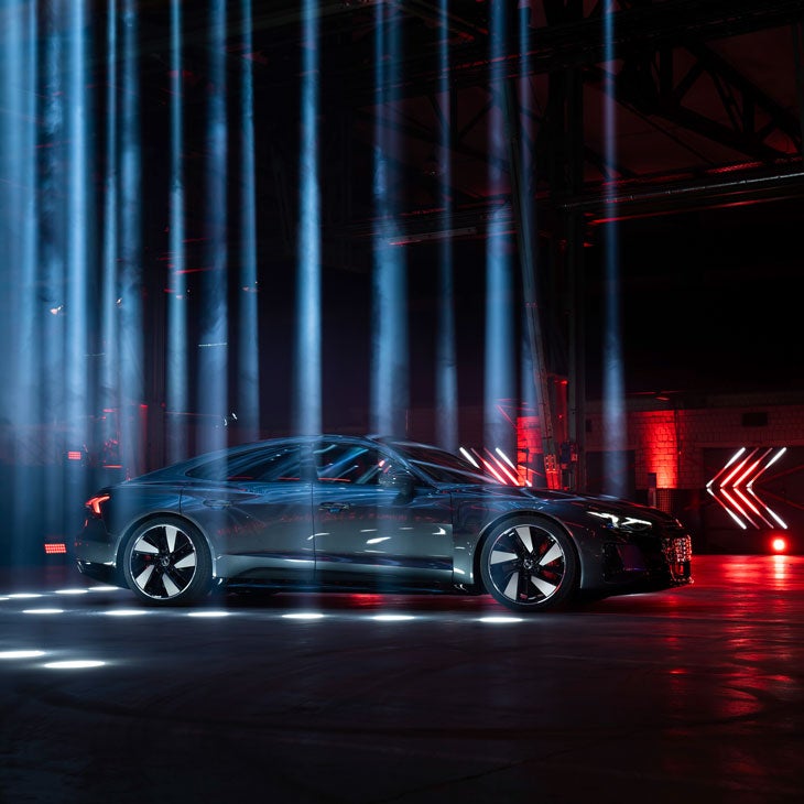 Une Audi RS e-tron GT stationnée dans une pièce sombre illuminée par des stroboscopes.