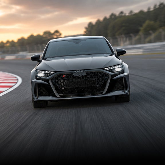 Front-view of an Audi sport vehicle accelerating on a racetrack.