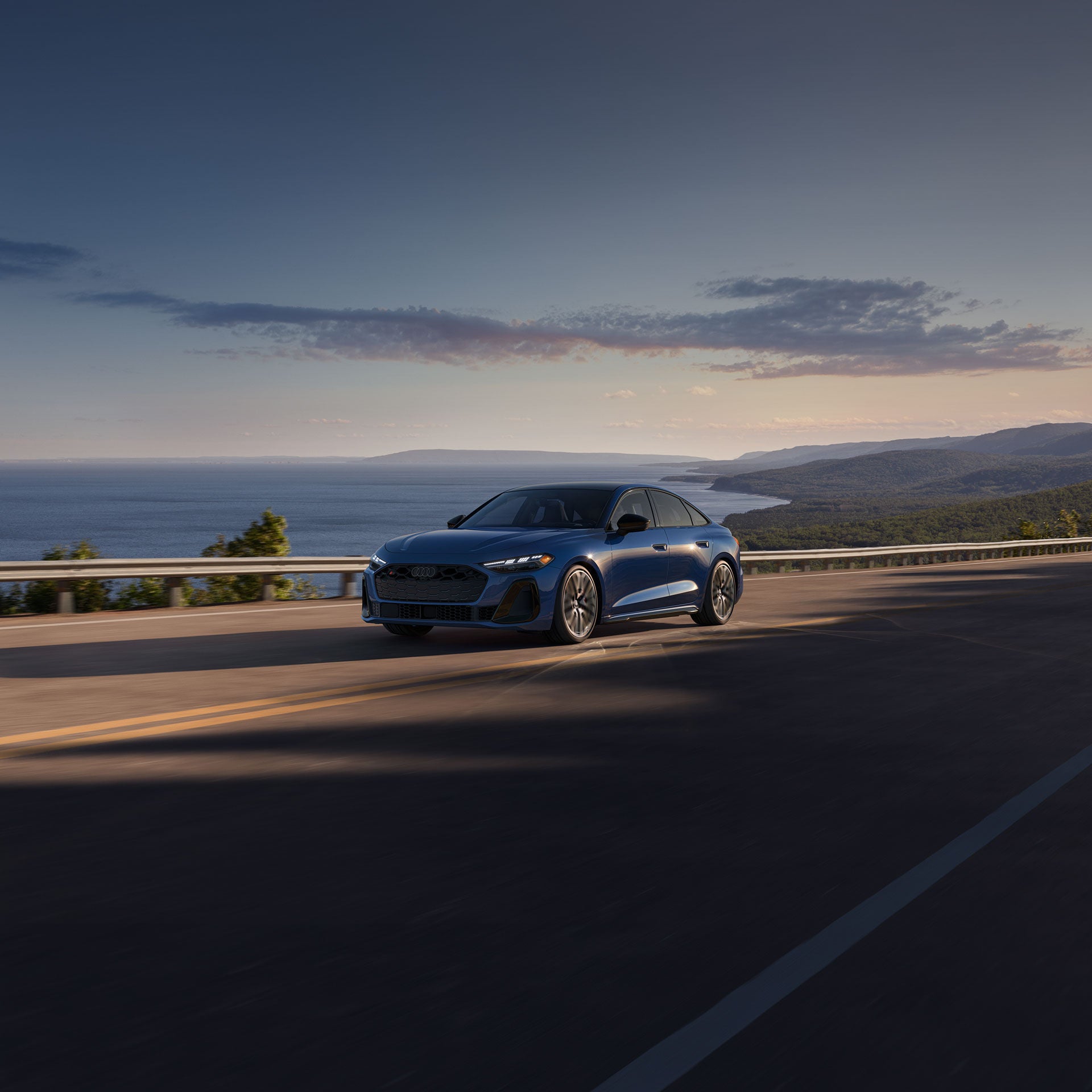 Three-quarter front view of the Audi S5 accelerating on an oceanside road.