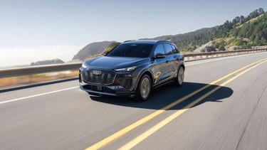 Three-quarter front view of the Audi Q6 e-tron accelerating on a hillside road.