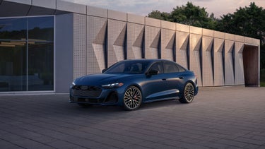 Three-quarter front view of the Audi S5 parked by a modern building.
