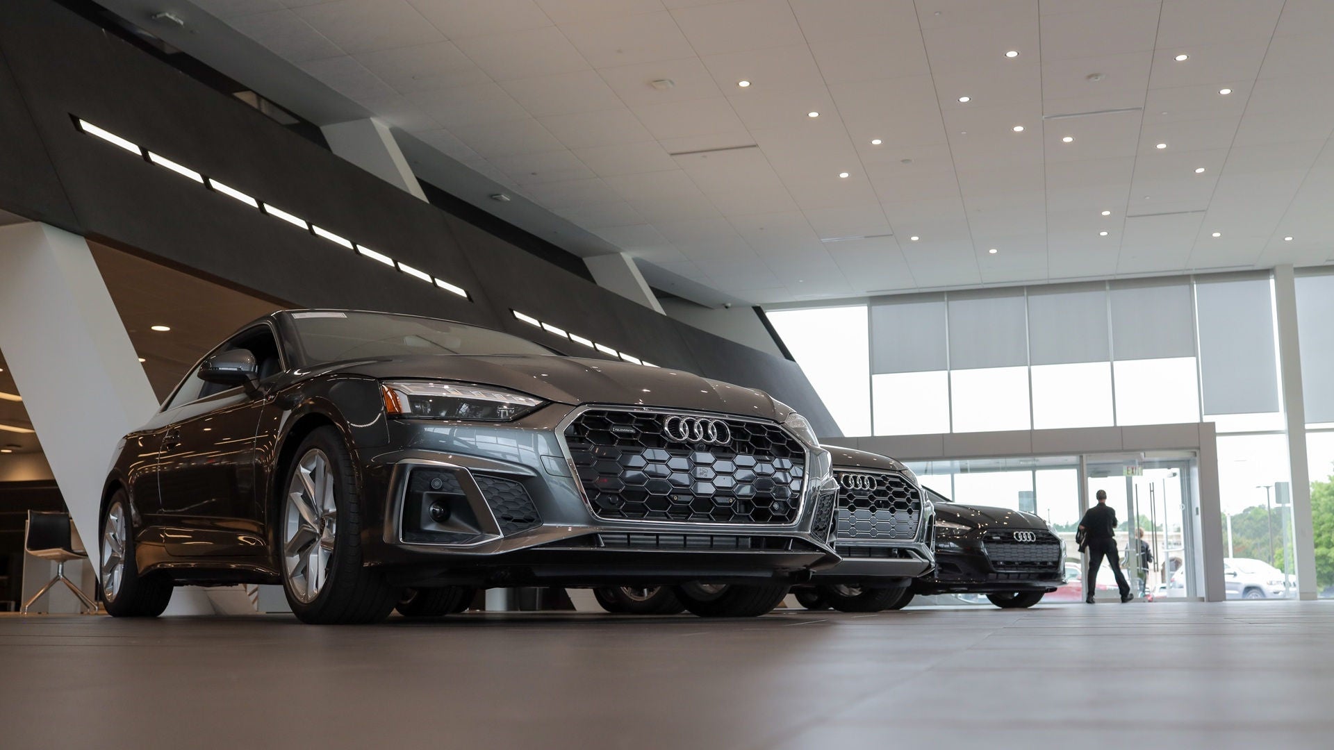 A row of 3 Audi cars parked inside of the showroom.