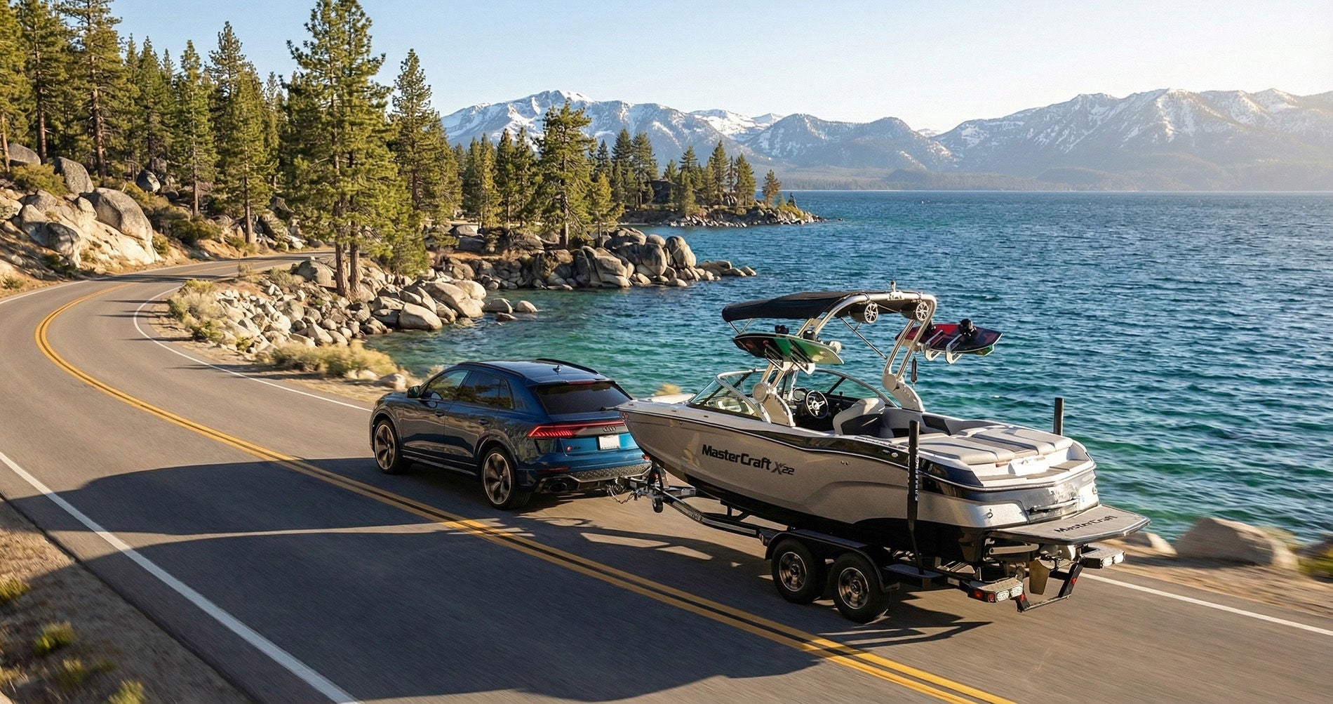 2026 Audi Q8 towing a wakeboarding boat along the shore of Lake Tahoe