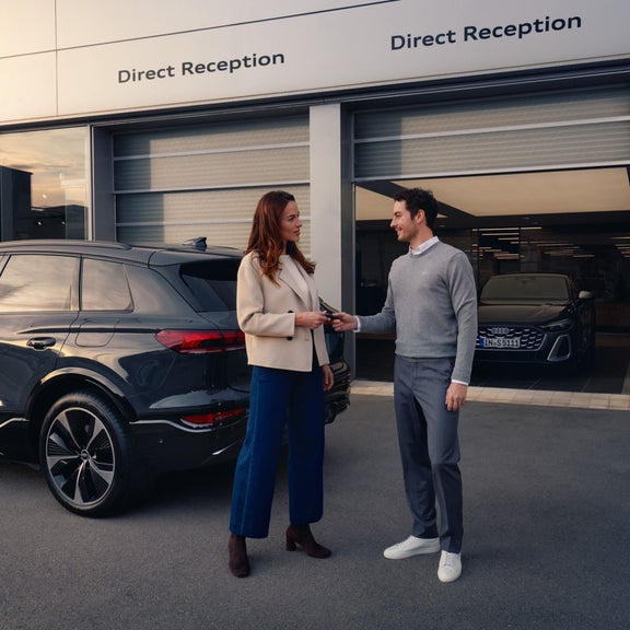 Audi employee explaining the Audi Financial Services Newcomer program to a customer.