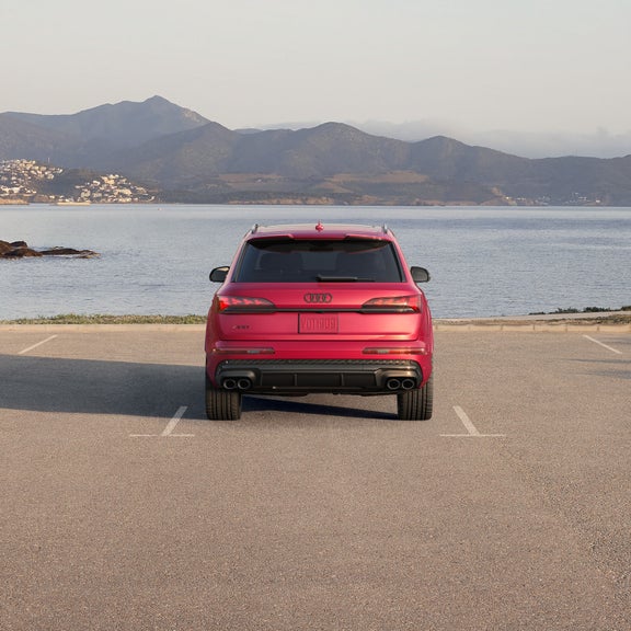 Rear profile of a red Audi SQ7 parked by a waterfront.