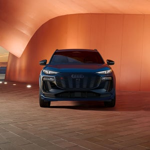 Front profile of the Audi SQ6 e-tron parked in front of a modern building.