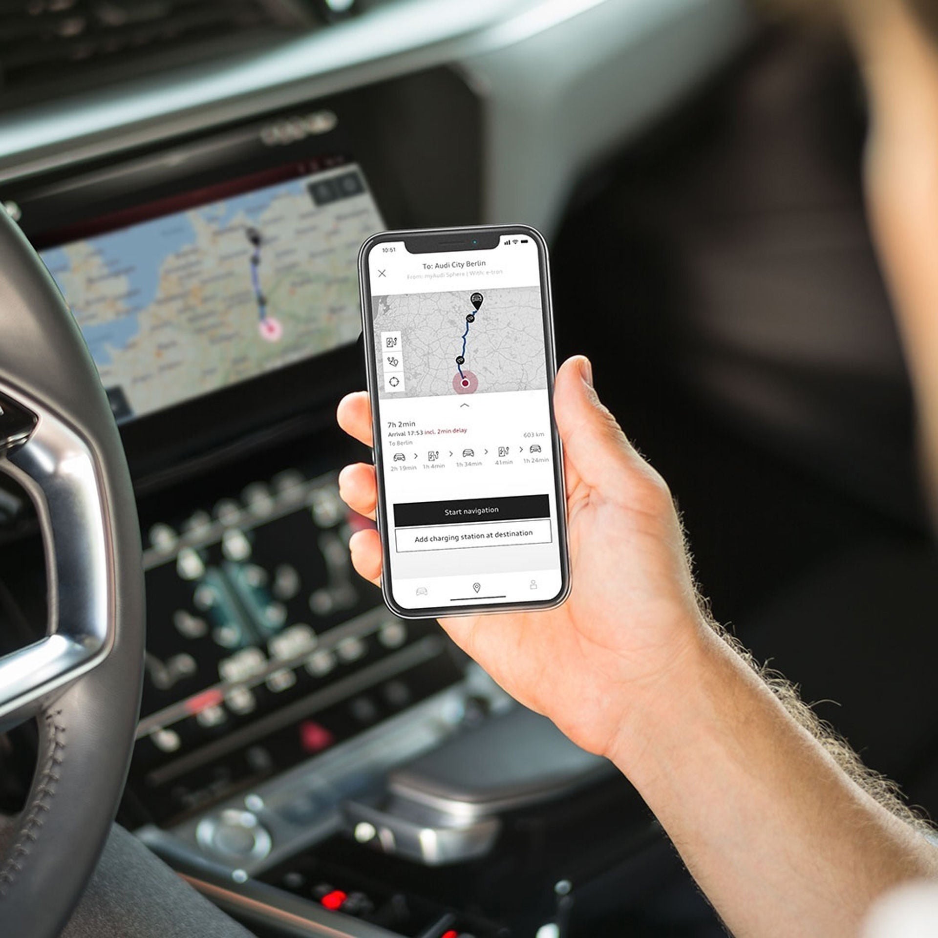A person sitting in the driver's seat while using the Audi e-tron route planner feature in the myAudi app.