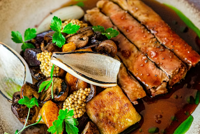 Plated fine dining dish with sliced steak and vegetables