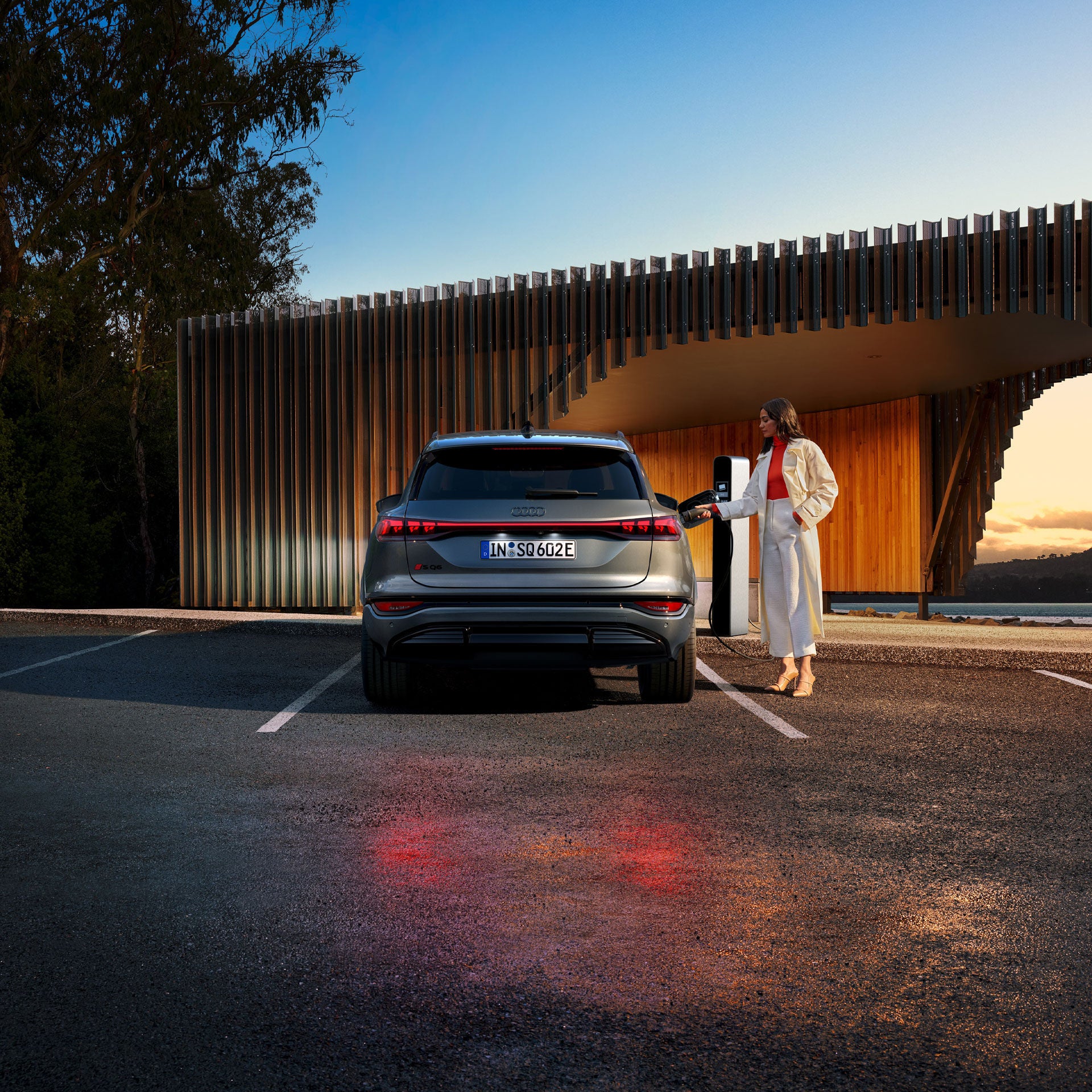 Vue arrière d’une femme qui recharge son Audi SQ6 e-tron.