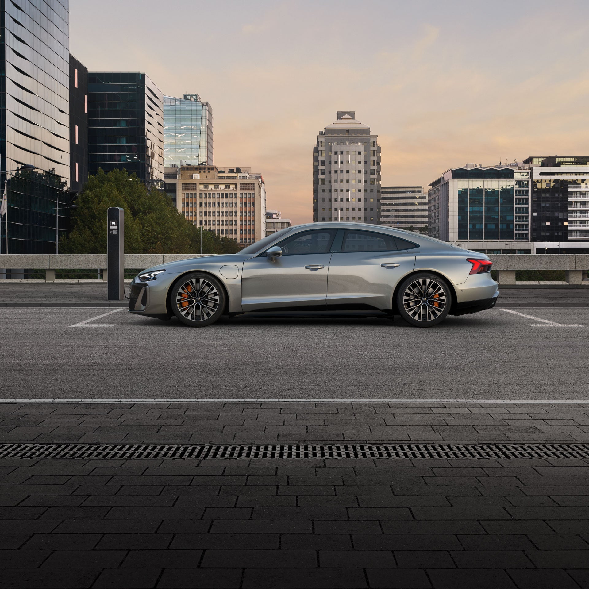 Side profile of the Audi S e-tron GT parked and charging on a city street.