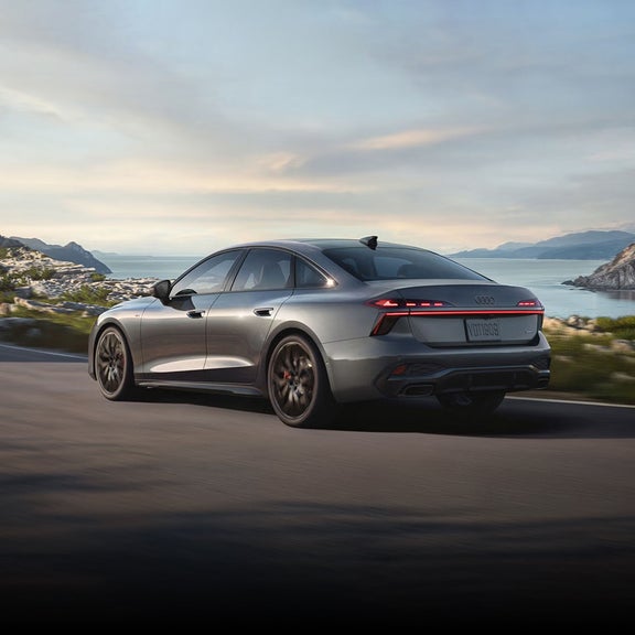 Three-quarter rear view of the Audi S5 accelerating on a waterside road.
