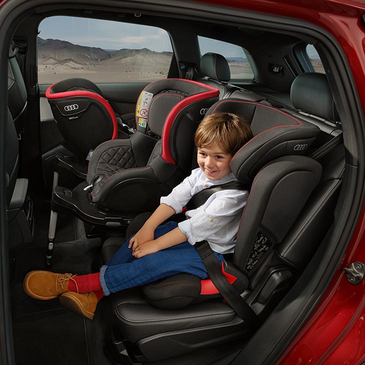 A photo of a small child strapped inside a safety seat inside of an Audi vehicle.