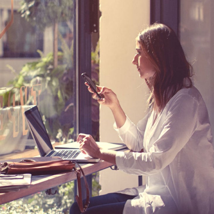 A woman sitting in a cafe as she makes the final monthly payment on her Audi.
