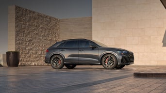Side view of the Audi SQ8 parked by a modern home.