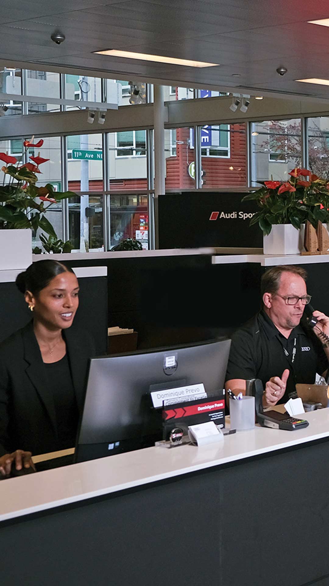 Receptionists working at desk in dealership